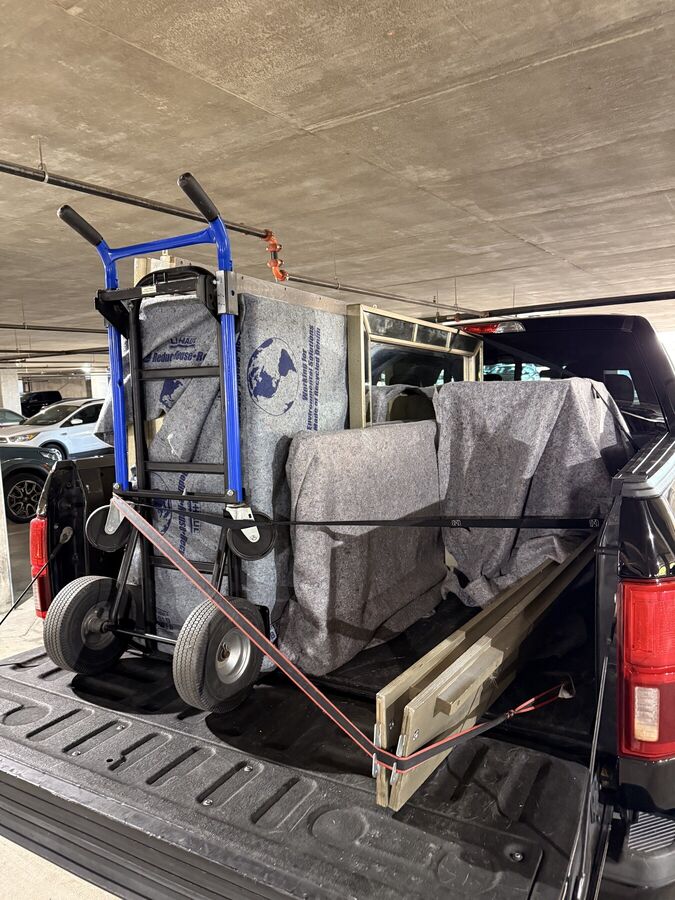 Furniture wrapped in moving blankets and strapped in the truck bed with a dolly