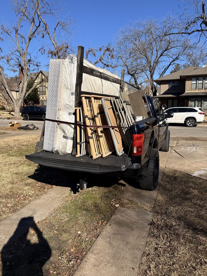Mattresses, bed frames and folding tables strapped into the truck at a residential driveway
