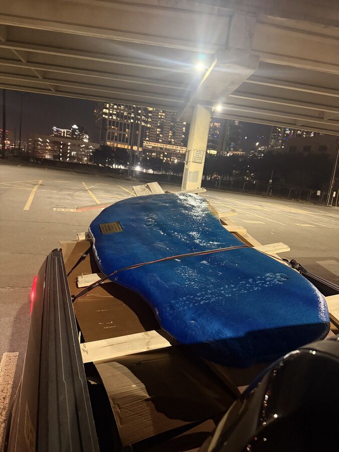 Large blue resin table top strapped and padded on the trailer at night